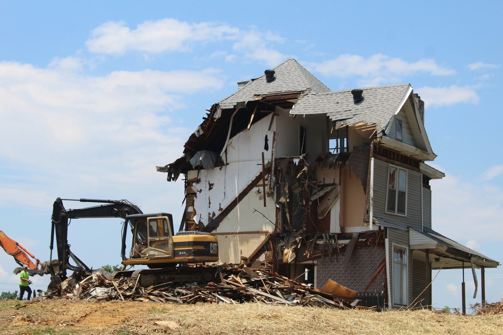 yellow and black heavy equipment near white and brown house during daytime